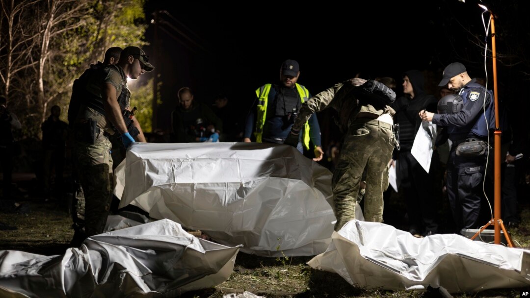 Anggota kepolisian Ukraina memeriksa jenazah dari para korban tewas dalam serangan roket Rusia yang menewaskan 51 orang di desa Hroza, Kharkiv, Ukraina, pada 5 Oktober 2023. (Foto: AP/Alex Babenko)