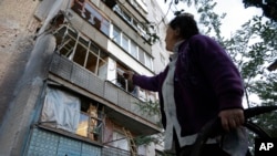 A woman points to a damaged building after shelling in the city of Slovyansk, Donetsk region, eastern Ukraine, June 29, 2014.