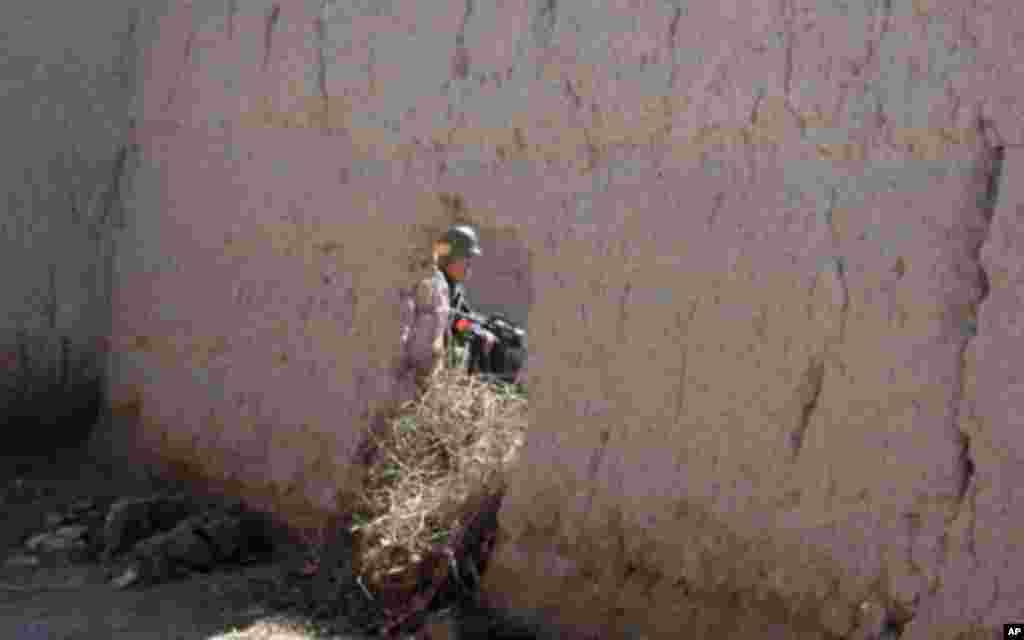 An Afghan soldier stands guard along the road as Secretary Gates walked to and from Tabin Village