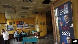 Men sit in a tea house in Istanbul, with a campaign poster of Prime Minister Recep Tayyip Erdogan on display nearby, June 9, 2011