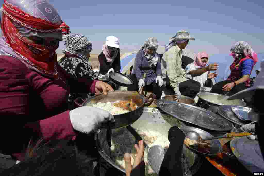 Residents from Qamishli distribute food to displaced people from the minority Yazidi sect, who fled the violence in the Iraqi town of Sinjar, at Nowruz refugee camp in Qamishli, northeastern Syria on the border with Kurdistan August 16, 2014. REUTERS/Yous