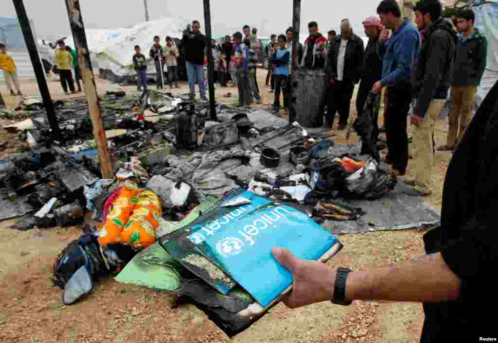 Syrian refugees search for their belongings at a burned tent at the Al Zaatari Syrian refugee camp, January 28, 2013.