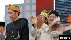 FILE - A freshly released dove is seen near presidential challenger Prabowo Subianto, right, as Indonesian Pesident Indonesian President Joko Widodo looks on during a ceremony marking the start of the campaigning period for next year's presidential election.