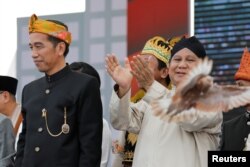 FILE - A freshly released dove is seen near presidential challenger Prabowo Subianto, right, as Indonesian Pesident Indonesian President Joko Widodo looks on during a ceremony marking the start of the campaigning period for next year's presidential election in Jakarta, Indonesia, Sept. 23, 2018.