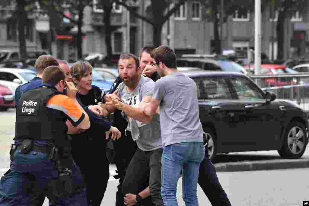 Police try to calm a man at the scene of a shooting in Liege, Belgium. A gunman killed three people, including two police officers in Liege, a city official said. Police later killed the attacker, and other officers were wounded in the shooting.