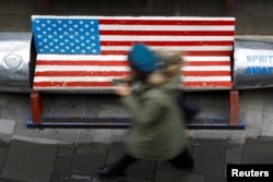 A woman walks past a bench painted in the colors of the U.S. flag, outside a clothing store in Beijing, China, Jan. 7, 2019.