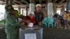 Electoral workers help an elderly woman cast her ballot at a makeshift polling station under a bridge during the runoff election in Jakarta, Indonesia, April 19, 2017. 