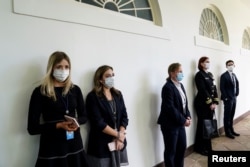 Anggota staf Gedung Putih dan dinas keamana federal Secret Service di lorong West Wing sebelum konferensi pers Presiden Donald Trump mengenai pandemi virus corona, di Gedung Putih, Washington, 11 Mei 2020. (Foto: Reuters)