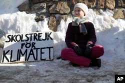 FILE - Climate activist Greta Thunberg poses for media outside the congress center where the World Economic Forum take place in Davos, Switzerland, Jan. 25, 2019. The poster reads: "School strike for the climate."