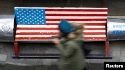 A woman walks past a bench painted in the colors of the U.S. flag, outside a clothing store in Beijing, China, Jan. 7, 2019. 