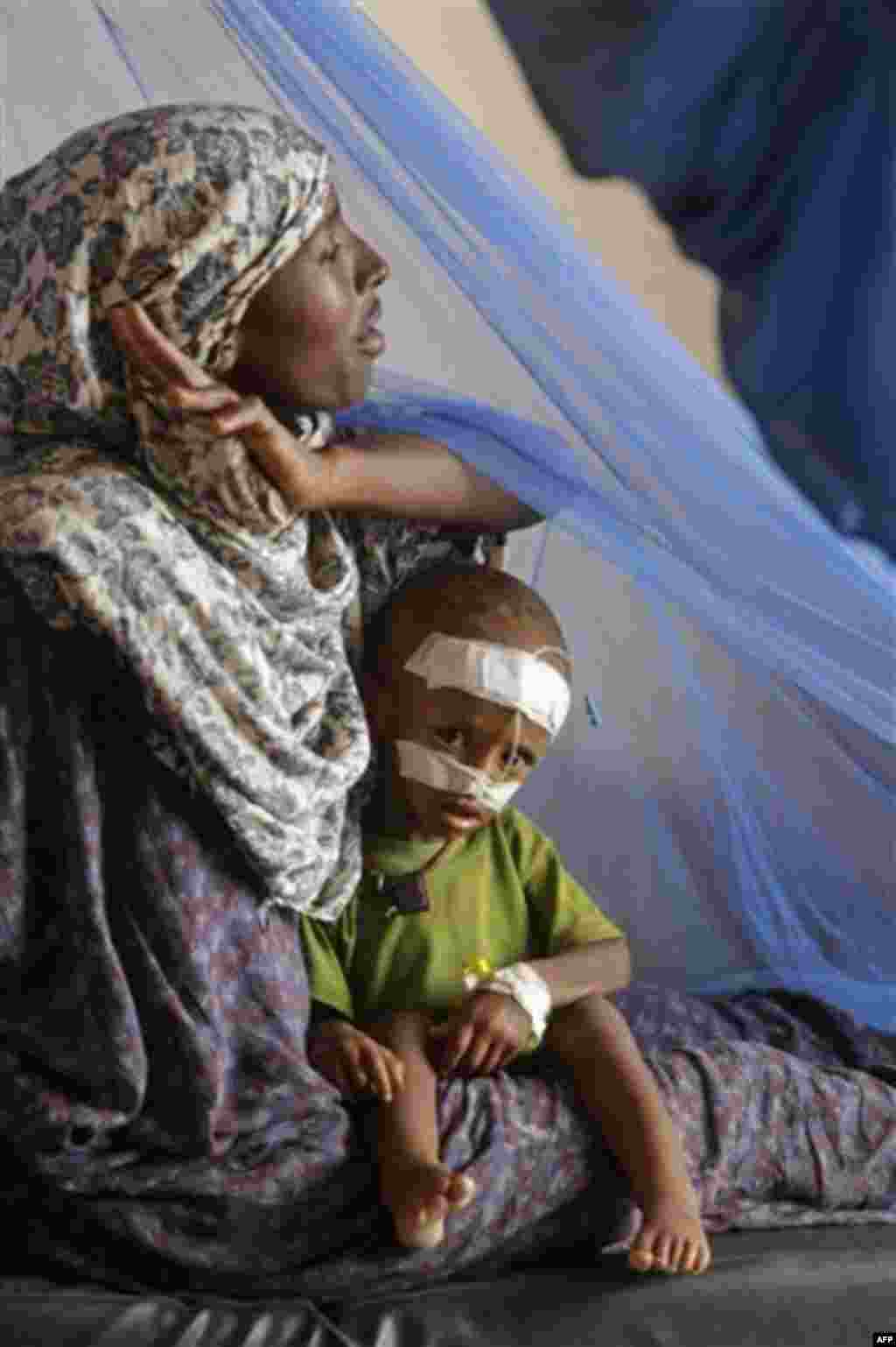 A woman sits with her child at a local hospital to receive treatment for malnutrition at the border town of Dadaab, Kenya, Saturday, July 23, 2011. People who can barely stay on their feet due to hunger walk for days or even weeks through parched waste