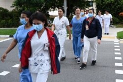 FILE - Medical staff are seen walking to the National Centre for Infectious Diseases building, at Tan Tock Seng Hospital, in Singapore, Jan. 31, 2020.