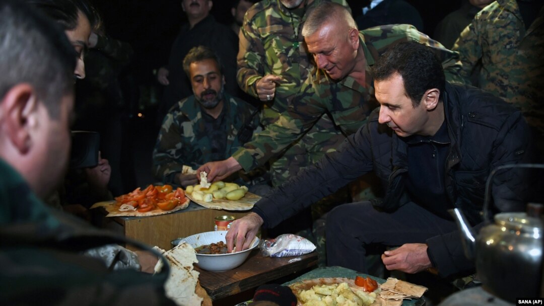 Suriya Prezidenti Bashar al-Assad harbiy bazada askarlar bilan ovqatlanmoqda, Damashq, 31-dekabr, 2014-yil.