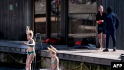 People enjoy the warm weather at Sandkaj Havnebad in Copenhagen Harbour, Denmark, on March 30, 2021.