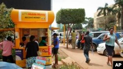 FILE - Ugandans use a mobile money point in Kampala, Uganda, Sept. 29, 2016.