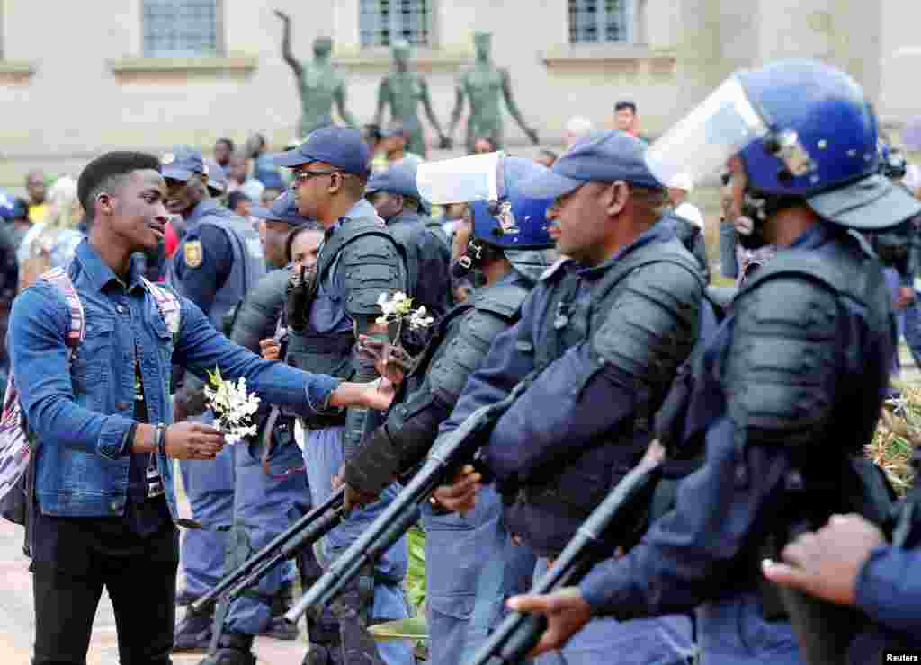 남아프리카공화국 수도 요하네스버그에 있는 비트바테르스란트 대학교에 진행된 무상 교육 요구 시위로 학생과 경찰이 충돌한 직후, 시위대원이 경찰에 꽃을 건네고 있다.