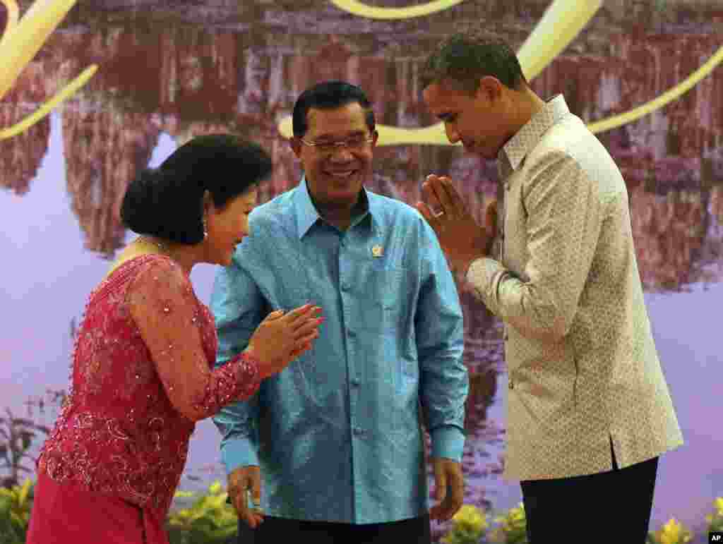 US President Barack Obama, right, returns a greeting to Bun Rany, wife of Cambodian Prime Minister Hun Sen, center, prior to a gala dinner in Phnom Penh, Cambodia, November 19, 2012.