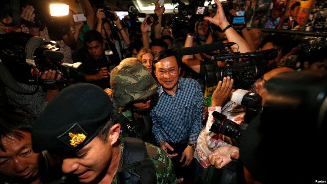 Mantan Menteri Pendidikan Thailand, Chaturon Chaisang (tengah), dikawal ketat oleh tentara dan dikerumuni oleh wartawan seusai memberikan sambutan di Klub Koresponden Asing di Bangkok, Thailand (27/5).