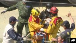 In this image made from video, Lee Tsung-tien, 42, is attended to by rescue workers after he was pulled out conscious from a building which collapsed after an earthquake in Tainan, Taiwan, Monday, Feb. 8, 2016.