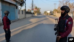 Security officials stand guard on a blocked road leading to a counter-terrorism center where several Pakistani Taliban detainees have taken police officers and others hostage inside the compound, in Bannu, a district in the Pakistan's Khyber Pakhtunkhwa province, Dec. 19, 2022. 