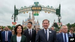 U.S. Commerce Secretary Gina Raimondo, left is escorted by officials as she tour the Shanghai Disneyland in Shanghai, China, Wednesday, Aug. 30, 2023. (AP Photo/Andy Wong, Pool)