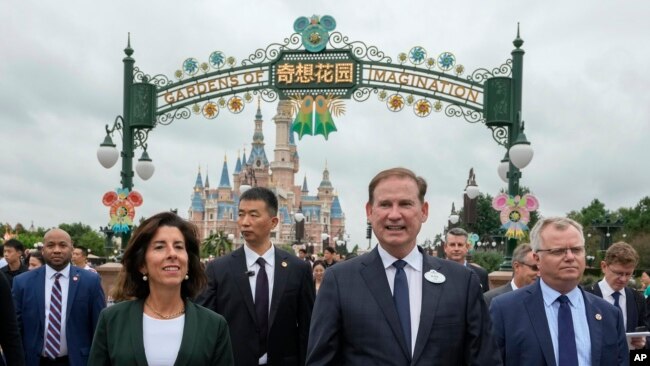 U.S. Commerce Secretary Gina Raimondo, left is escorted by officials as she tour the Shanghai Disneyland in Shanghai, China, Wednesday, Aug. 30, 2023. (AP Photo/Andy Wong, Pool)