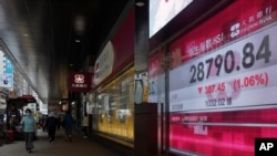 La gente pasa frente a la pizarra electrónica de un banco que muestra el índice de acciones de Hong Kong en la Bolsa de Valores de Hong Kong el lunes 8 de marzo de 2021. 