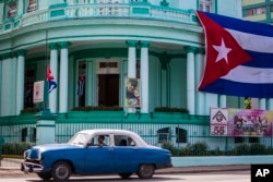 A Cuban flag flies at half-staff, left, and a picture of Fidel Castro decorates the headquarters of the Committees for the Defense of the Revolution one day after Castro died in Havana, Cuba, Nov. 26, 2016.
