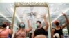 Protest leaders wearing crop tops and showing the three-finger salute, pose in front of Thailand's Princess Sirivannavari fashion boutique at Siam Paragon shopping center, as they protest against the monarchy, in Bangkok, Dec. 20, 2020.