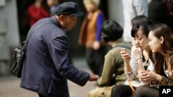 FILE - A beggar asks for money from people sitting at a shopping mall in Shanghai, China, Apr. 19, 2012. Many of China's nouveau riche now are thinking of giving back to society.