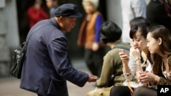 FILE - A beggar asks for money from people sitting at a shopping mall in Shanghai, China, Apr. 19, 2012. Many of China's nouveau riche now are thinking of giving back to society.