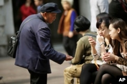 Ảnh tư liệu - Một người đàn ông xin tiền từ những người đang ngồi ở một trung tâm mua sắm ở Thượng Hải, Trung Quốc, ngày 19 tháng 4 năm 2012.