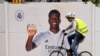 Un ciclista pasa frente a un afiche de Vinicius Junior, el delantero brasileño del Real Madrid, frente al estadio Santiago Bernábeu, el lunes 22 de mayo de 2023 en Madrid.