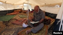 A Palestinian man reads the Koran inside a tent during the holy month of Ramadan, at a protest camp near the Israel-Gaza border in the central Gaza Strip, May 17, 2018. 