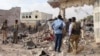 In this image taken from video on March 12, 2025, observers and security officers look over the aftermath of a car bomb explosion the previous day at a hotel in the central Somali city of Beledweyne.