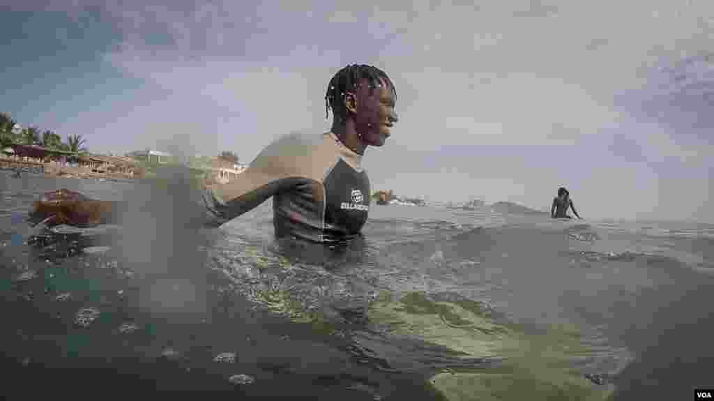 Pape Diouf waits for a wave in waters off Dakar, Senegal. (Annika Hammerschlag/VOA)