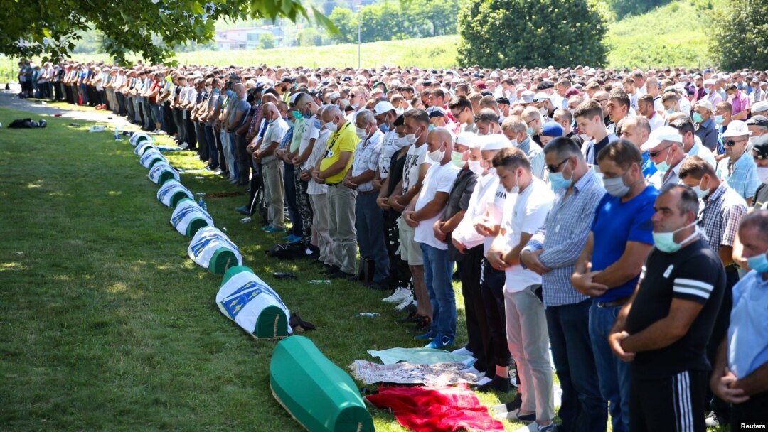 People pray near coffins at a graveyard during a mass funeral in Potocari near Srebrenica, Bosnia and Herzegovina July 11, 2020.