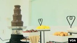 Pembuat coklat Hillary Bradley menyajikan beragam makanan, seperti pretzel, kue-kue kering, marshmallow, dan buah-buahan, dengan coklat air mancur atau chocolate fountain.