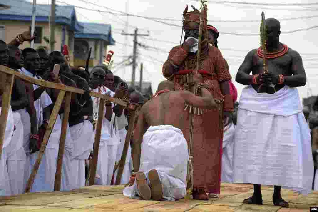 A palace aide kneels down before newly crowned 40th Monarch of the Benin kingdom Oba Ewuare II on a wooden bridge during a rite to mark his coronation in Benin City, midwest Nigeria.