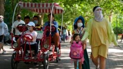 FILE - Chinese families wearing face masks bring their children to a public park during International Children's Day in Beijing, June 1, 2021. China's leaders have announced they will let all couples have three children instead of two, hoping to counter the rapid aging of Chinese society.