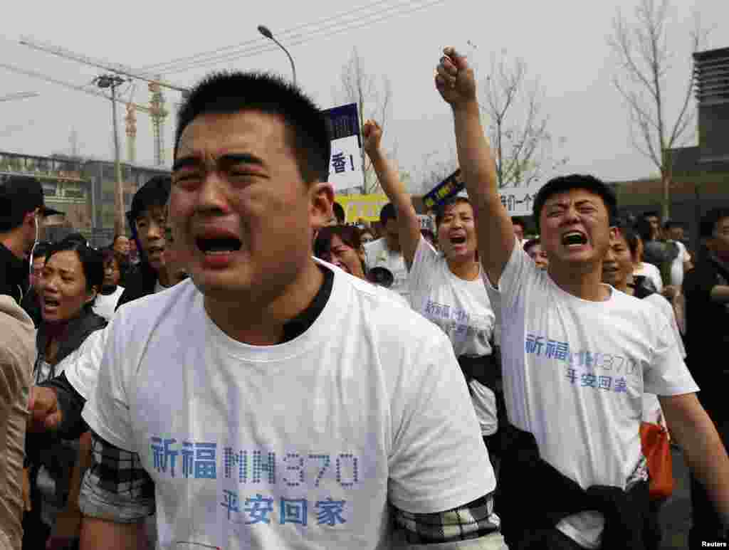 Family members of passengers onboard flight MH370 cry as they shout slogans during a protest in front of the Malaysian embassy in Beijing, March 25, 2014. 