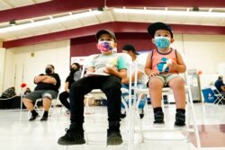 FILE - Oliver Estrada, 5, front left, waits with his brother Adriel, 2, after Estrada received the first dose of the Pfizer COVID-19 vaccine at an Adelante Healthcare community vaccine clinic at Joseph Zito Elementary School, in Phoenix, Nov. 6, 2021.