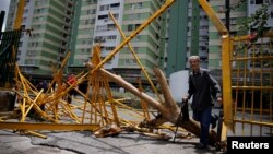 A man walks through a broken main gate after opposition supporters and security forces clashed in and outside residential buildings on Tuesday according to residents, in Caracas, Venezuela, June 14, 2017.