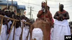 Un collaborateur du palais s’agenouille devant le 40ème monarque du royaume Bénin, Oba Ewuare II, nouvellement couronné sur un pont en bois au cours d'un rite d'intronisation à Bénin City au Nigeria.