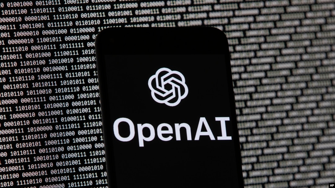 ARCHIVO - El logo de OpenAI aparece en un teléfono celular frente a la pantalla de una computadora con datos binarios aleatorios, el 9 de marzo de 2023, en Boston.