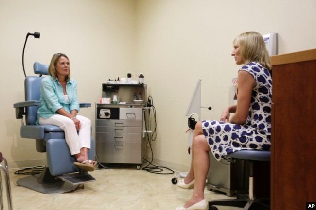 In this Aug. 1, 2014 photo, Louise Danzig, of Montauk, N.Y., left, discusses with Dr. Erin McGintee her progress after Danzig landed in the hospital because a tick bite gave her a severe allergic reaction. (AP Photo/Rachelle Blidner)