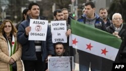 Demonstrators holding a Free Syria flag and placards reading "Stop the killing in Syria" take part in a protest outside the United Nations (UN) offices in Geneva, on Jan. 29, 2016 on the opening day of Syrian peace talks.