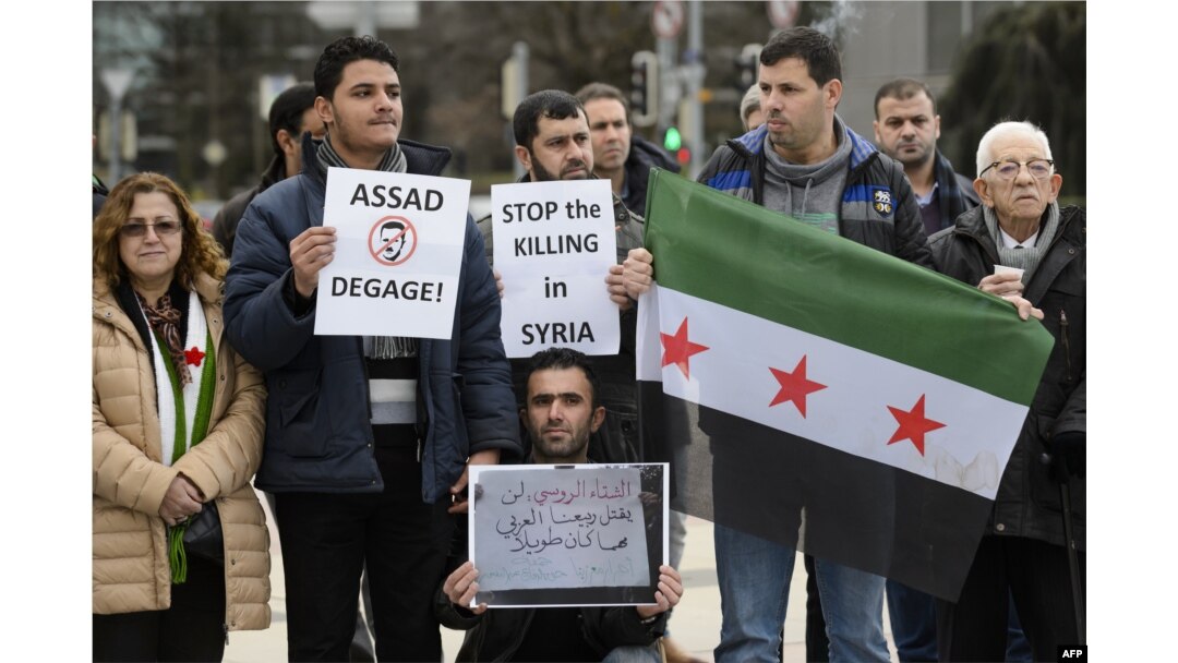 Demonstrators holding a Free Syria flag and placards reading "Stop the killing in Syria" take part in a protest outside the United Nations (UN) offices in Geneva, on Jan. 29, 2016 on the opening day of Syrian peace talks.