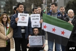 Demonstrators holding a Free Syria flag and placards reading "Stop the killing in Syria" take part in a protest outside the United Nations (UN) offices in Geneva, on Jan. 29, 2016 on the opening day of Syrian peace talks.