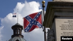 FILE - The U.S. flag and South Carolina state flag flies at half staff to honor the nine people killed in the Charleston murders as the confederate battle flag also flies on the grounds of the South Carolina State House in Columbia, S.C., June 20, 2015. 